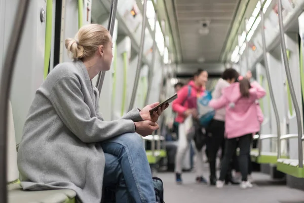 地下鉄公共交通機関で旅行中にスマートフォンを使用して美しいブロンドの女性. — ストック写真