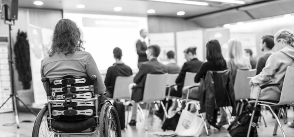 坐在轮椅上无法辨认的妇女参加商务会议讲座的后视图. — 图库照片