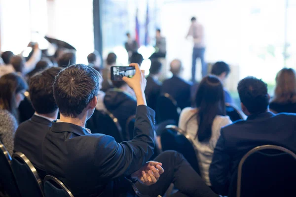 Empresário tira uma foto da apresentação empresarial na sala de conferências usando smartphone . — Fotografia de Stock