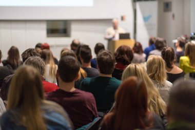 Üniversitedeki konferans salonunda sunum yapan adam.