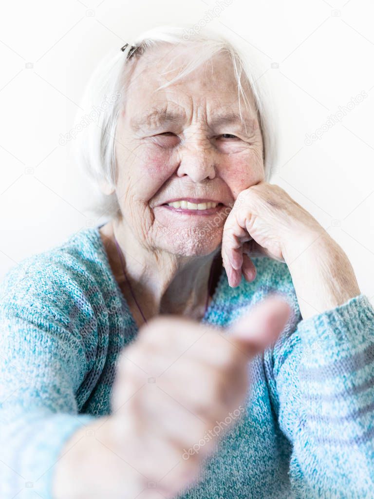 Happy 96 years old elderly woman giving a thumb up and looking at camera.