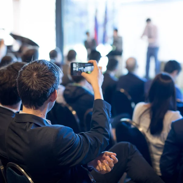 Empresário tira uma foto da apresentação empresarial na sala de conferências usando smartphone . — Fotografia de Stock