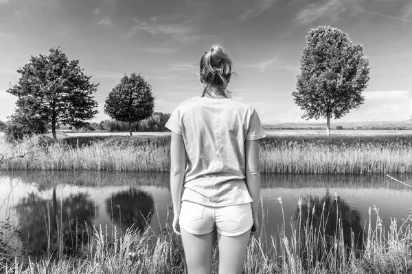 Junge Frau in lässiger Sommerkleidung genießt die schöne Aussicht auf die friedliche Landschaft. — Stockfoto