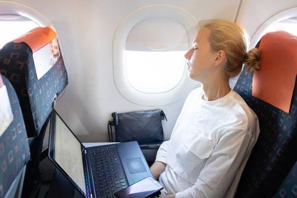 Уставшая деловая женщина, дремлющая в самолете во время своей деловой поездки по делам . — стоковое фото