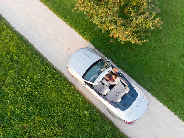 Luchtfoto van succesvolle man rijden en genieten van zijn zilveren cabriolet luxe sportwagen op de open land zijweg — Stockfoto