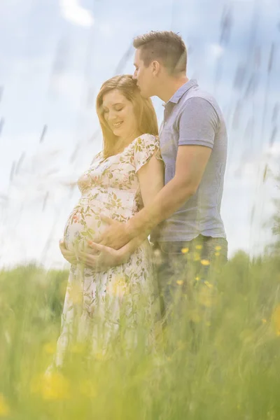 Jong gelukkig zwanger paar knuffelen in de natuur. — Stockfoto