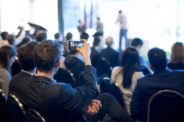 Empresário tira uma foto da apresentação empresarial na sala de conferências usando smartphone . — Fotografia de Stock