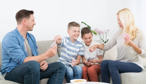 Happy young family playing card game at home.