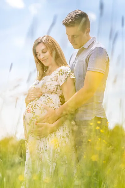 Młody szczęśliwy w ciąży para przytulanie w przyrodzie. — Zdjęcie stockowe