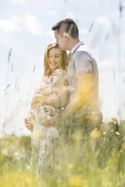 Young happy pregnant couple hugging in nature. — Stock Photo, Image