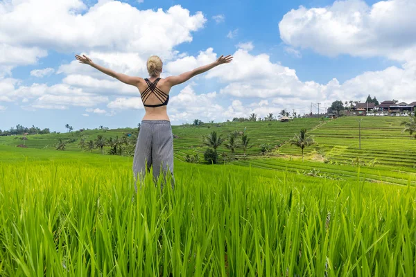 Entspannte, gesunde, sportliche Frau, Arme in den Himmel gereckt, Natur pur auf schönen grünen Reisfeldern auf Bali genießend. — Stockfoto