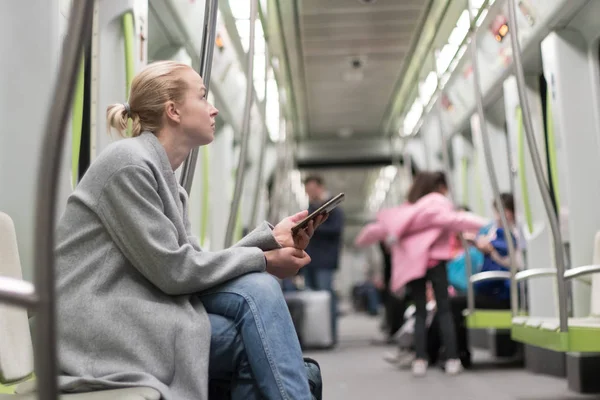 Wanita pirang cantik menggunakan telepon pintar saat bepergian dengan angkutan umum metro. — Stok Foto