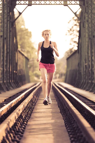 Mulher esportiva ativa correndo em trilhos ferroviários. — Fotografia de Stock