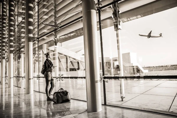 Giovane donna in attesa in aeroporto, guardando attraverso la finestra del cancello . — Foto Stock