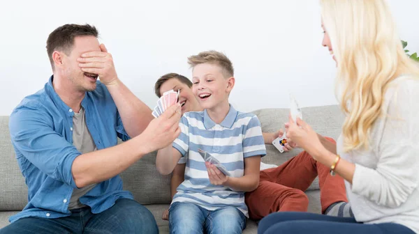 Happy young family playing card game at home.