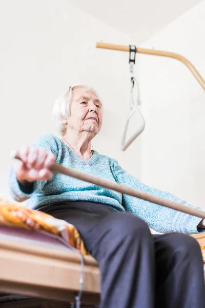 Пожилая 96-летняя женщина упражняется с палкой сидя на ее плохо. — стоковое фото
