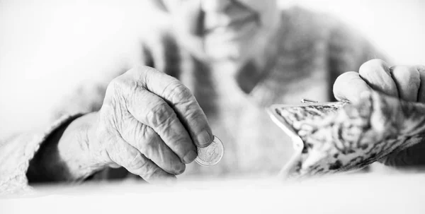 Detaillierte Nahaufnahme Foto von nicht wiederzuerkennenden älteren Frauen Hände, die Reste von Münzen aus der Rente in ihrer Brieftasche zählen, nachdem sie Rechnungen bezahlt. Schwarz-Weiß-Bild. — Stockfoto