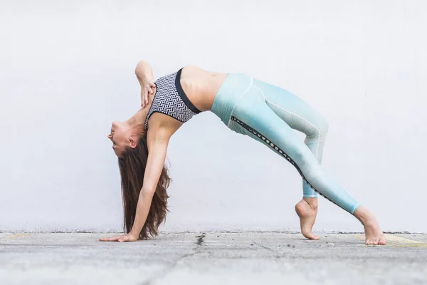 FIT sportowy aktywny dziewczyna w odzieży sportowej robi joga ćwiczenia fitness przed szarą ścianę, sporty na świeżym powietrzu, styl miejski — Zdjęcie stockowe