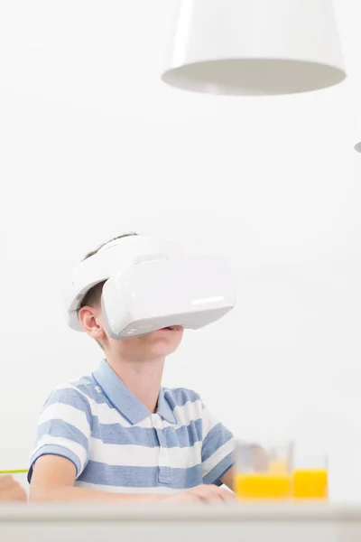 Дивовижна дитина використовує гарнітури віртуальної реальності, сидячи за обіднім столом . — стокове фото