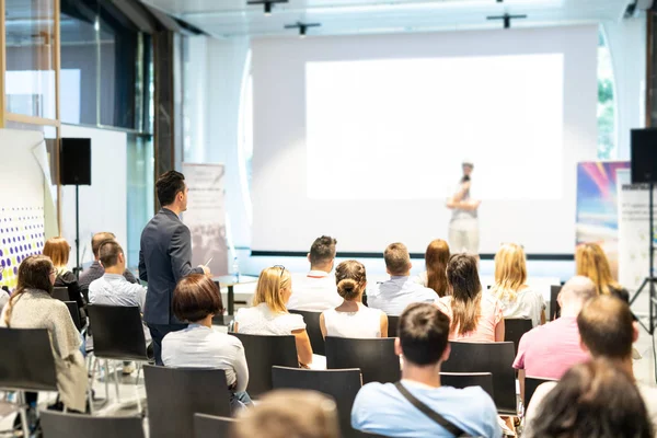 Empresário em audiência de pé e fazendo perguntas para speeker na conferência de negócios. — Fotografia de Stock