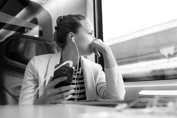 Trenle seyahat ederken cep telefonundan podcast dinleyen düşünceli iş kadını.. — Stok fotoğraf