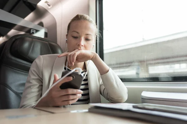 Podnikatelka komunikující na mobilním telefonu při cestování vlakem. — Stock fotografie