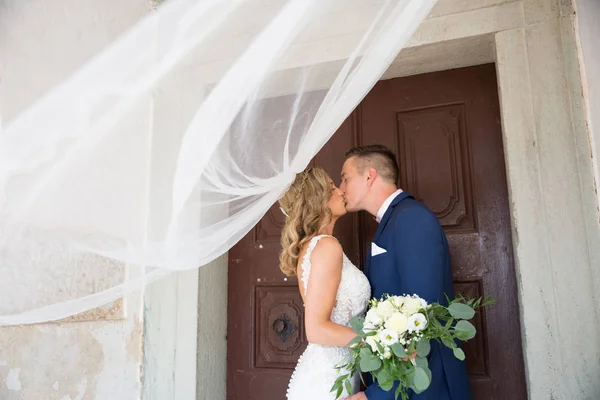 Le baiser. Mariée et marié s'embrassent tendrement à l'ombre d'un voile volant. Photo de mariage artistique noir et blanc . — Photo