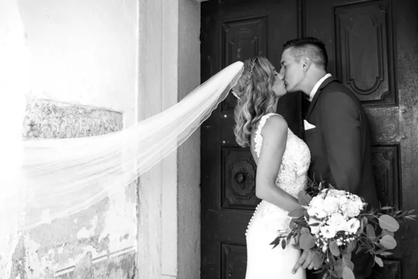 Le baiser. Mariée et marié embrasse tendrement devant le portail de l'église . — Photo