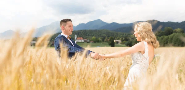 Bräutigam und Braut halten Händchen im Weizenfeld irgendwo in der slowenischen Landschaft. — Stockfoto