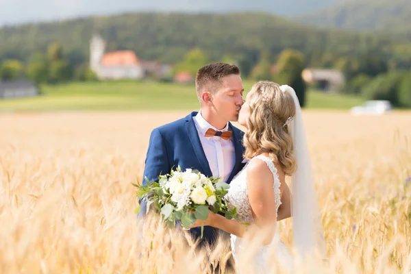 Brud och brudgum kyssar och kramar ömt i vete fältet någonstans på slovenska landsbygden. — Stockfoto