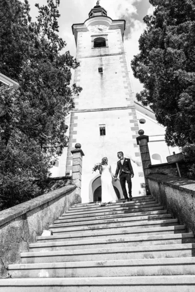 O Beijo. Noiva e noivo beija ternamente em uma escada na frente de uma pequena igreja local . — Fotografia de Stock