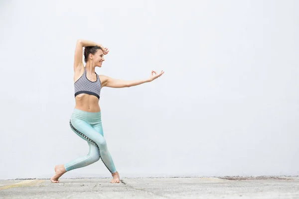 FIT sportowy aktywny dziewczyna w odzieży sportowej robi joga ćwiczenia fitness przed szarą ścianę, sporty na świeżym powietrzu, styl miejski — Zdjęcie stockowe
