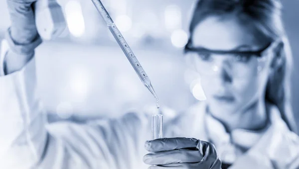 Joven científico pipeteando en laboratorio de ciencias de la vida. — Foto de Stock