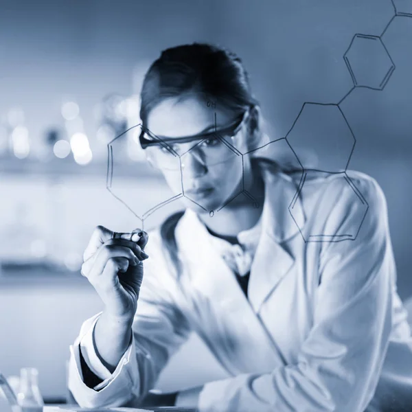 생명 과학 실험실에서 구조 화학 공식을 유리판에 쓰고 있는 자신있는 여성 연구원의 모습. — 스톡 사진