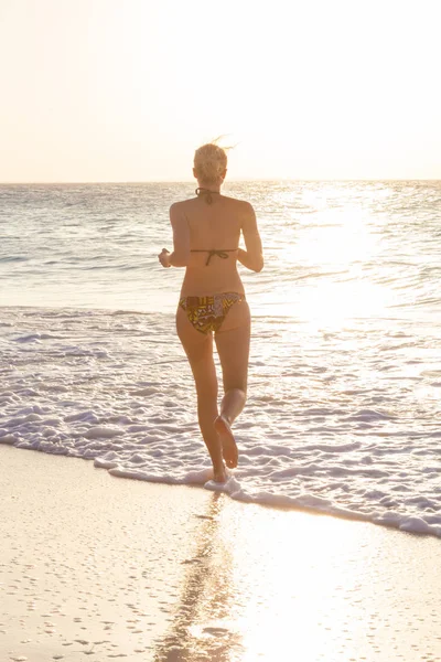 Vrouw met zonsondergang op het strand. — Stockfoto