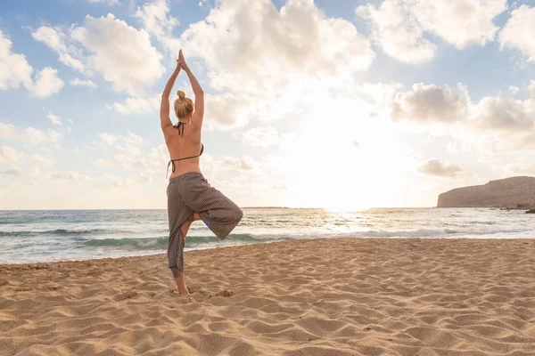 Mujer practicando yoga en la playa de mar al atardecer. —  Fotos de Stock