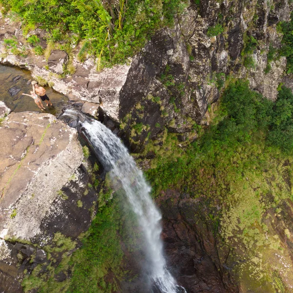 モーリシャス島のブラックリバー渓谷国立公園の熱帯島ジャングルの500フィートの滝の端に立って、ドローンに手を振る旅行カップルの空中トップビュー — ストック写真