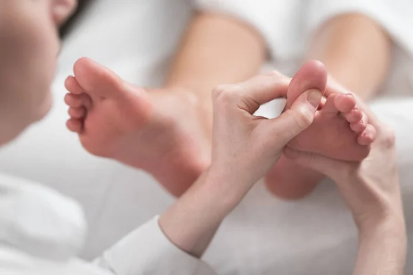 Profissional massagista feminino dando massagem reflexologia ao pé da mulher — Fotografia de Stock