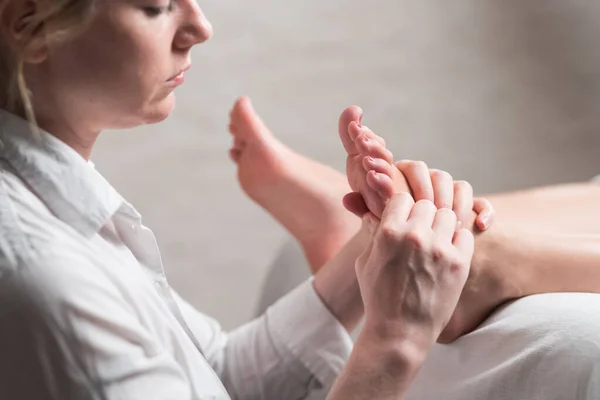 Profissional massagista feminino dando massagem reflexologia ao pé da mulher — Fotografia de Stock