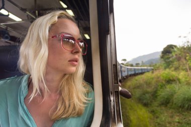 Mutlu gülümseyen kadın pencereden bakar Sri Lanka 'nın en güzel tren yolunda trenle seyahat eder.