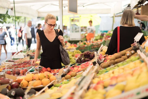 Donna che compra frutta e verdura al mercato alimentare locale. Banco di mercato con varietà di verdure biologiche — Foto Stock