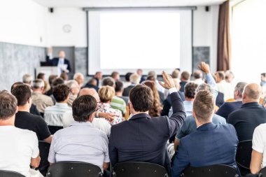 Benim bir sorum var. Bir grup iş adamı konferans salonunda oturuyor. İş adamı kolunu kaldırıyor. Konferans ve Sunum. İş ve Girişimcilik