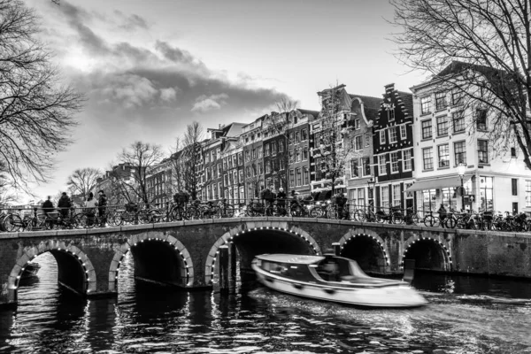 Prachtige rustige scene van de stad Amsterdam in de schemering. Fietsen langs de straat en over de brug over het kanaal. — Stockfoto