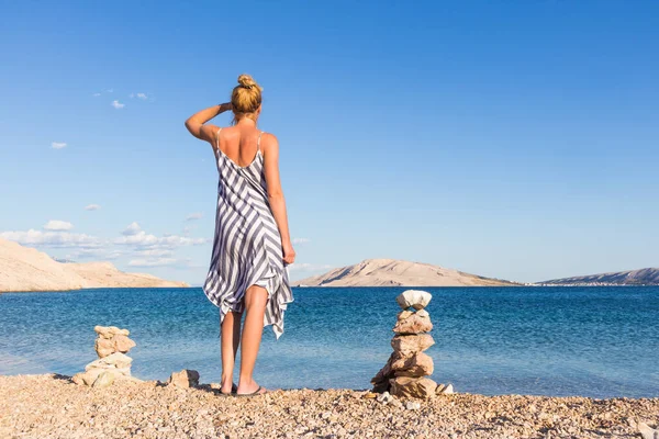 Šťastná bezstarostná žena se těší pozdní odpolední procházka na bílé oblázkové pláži na ostrově Pag, Chorvatsko — Stock fotografie