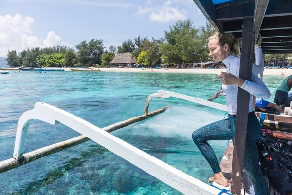 Hermosa viajera solista relajándose y disfrutando del hermoso mar azul en un barco de madera tradicional después de un viaje de buceo en las Islas Gili cerca de Bali, Indonesia — Foto de Stock