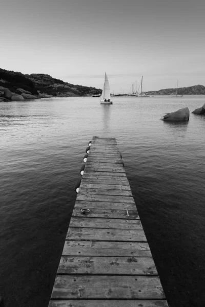 Houten pier en zeilboten varen in de avond rustige zee van prachtige Porto Rafael, Costa Smeralda, Sardinië, Italië. Symbool voor ontspanning, rijkdom, vrije tijd — Stockfoto