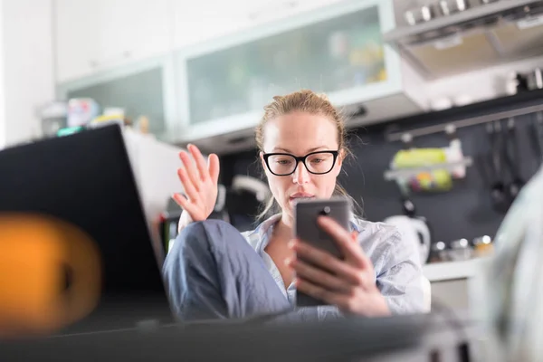 Stanna hemma och social distansering. Kvinna i vardagskläder som arbetar på distans från köksbordet. Videochatt med vänner, familj, företagskunder eller partners via sociala medier — Stockfoto