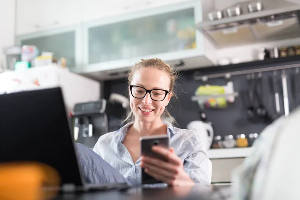 Quédate en casa y distanciamiento social. Mujer en su ropa casera informal trabajando remotamente desde la mesa de comedor de la cocina. Chat de vídeo utilizando las redes sociales con amigos, familiares, clientes de negocios o socios — Foto de Stock