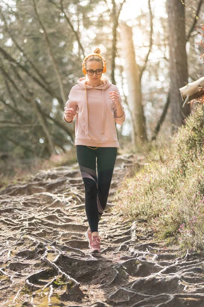 Mujer deportiva activa escuchando la música mientras corre en otoño bosque de otoño. Corredor femenino entrenando al aire libre. Estilo de vida saludable imagen de la joven mujer caucásica corriendo fuera —  Fotos de Stock