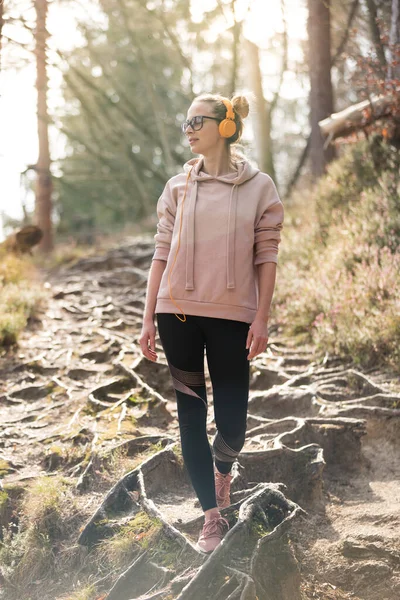 Femme sportive active à l'écoute de la musique lors d'une randonnée dans la forêt automnale d'automne. Joggeuse s'entraînant en plein air. Style de vie sain image de jeune femme caucasienne marchant sur le sentier de randonnée dans la nature — Photo